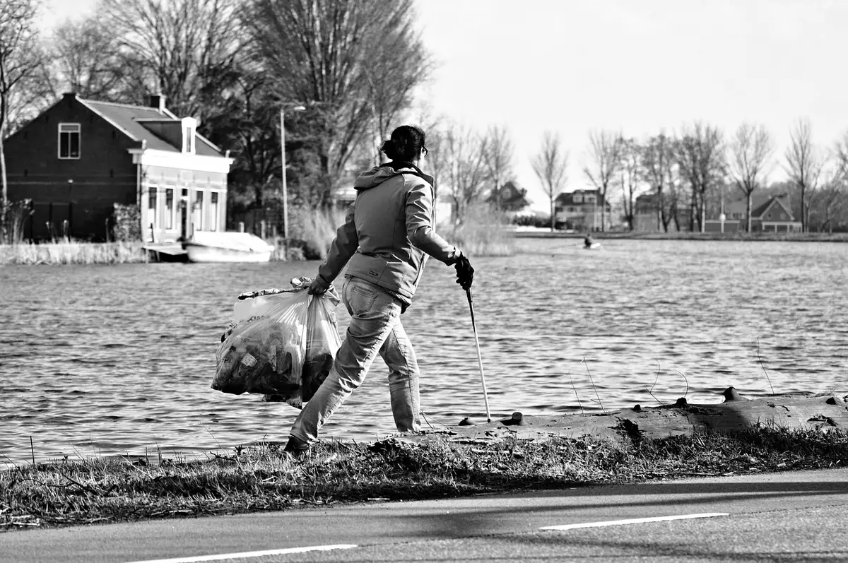 une femme marche avec des sacs de déchets qu'elle a ramassé