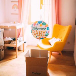 ballon avec welcome baby sortant d'un carton dans une chambre de bébé