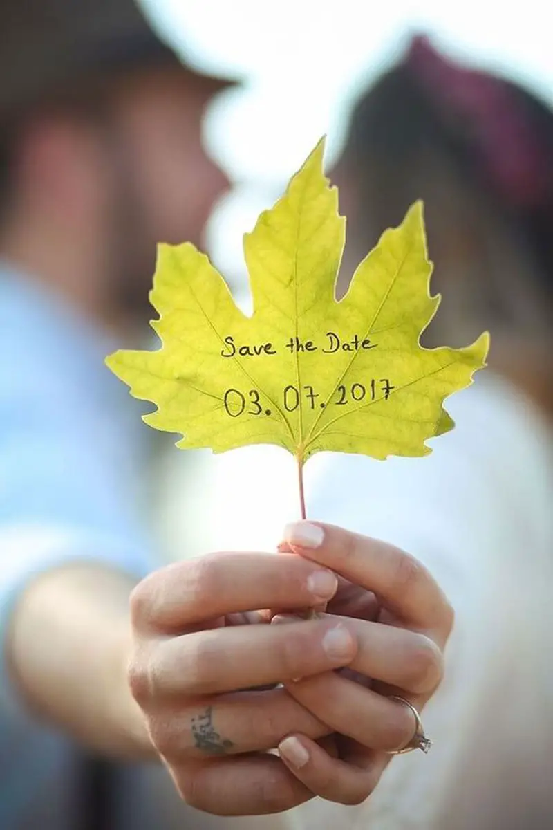 couple s'embrasse avec feuille d'arbre dans la main sur laquelle il y a une date